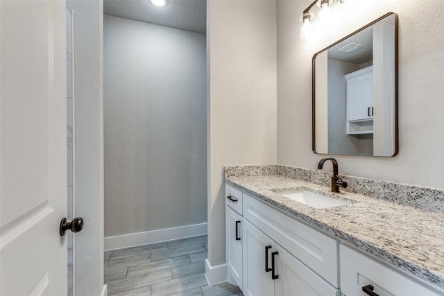 bathroom featuring vanity, baseboards, and wood finished floors