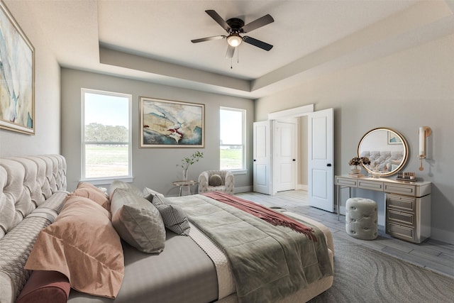bedroom with baseboards, a raised ceiling, and a ceiling fan