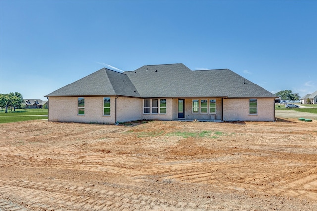 rear view of property with brick siding and a shingled roof