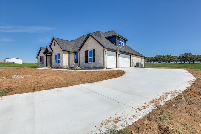 view of front facade featuring an attached garage, a front lawn, central AC unit, brick siding, and driveway