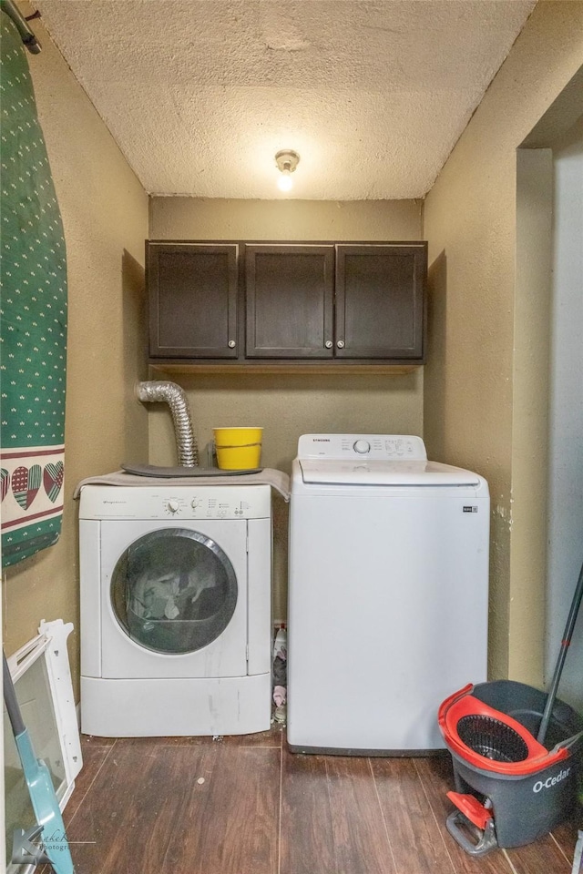 clothes washing area featuring washing machine and dryer, cabinet space, wood finished floors, and a textured ceiling
