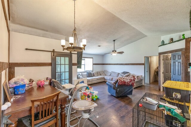 dining space featuring a textured ceiling, vaulted ceiling, a barn door, wood finished floors, and a ceiling fan
