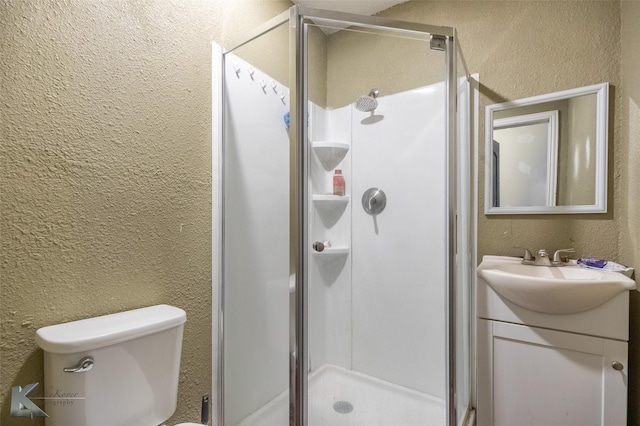 bathroom featuring a textured wall, a shower stall, vanity, and toilet