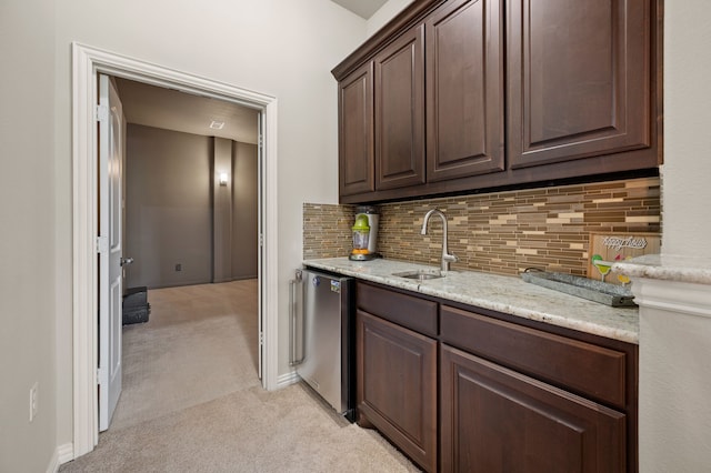 kitchen with a sink, light colored carpet, fridge, dark brown cabinets, and tasteful backsplash