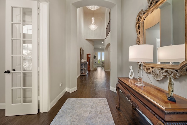 entrance foyer featuring arched walkways, dark wood-type flooring, and baseboards