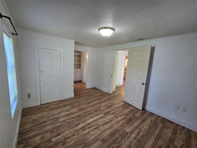 unfurnished bedroom featuring baseboards, a closet, visible vents, and wood finished floors