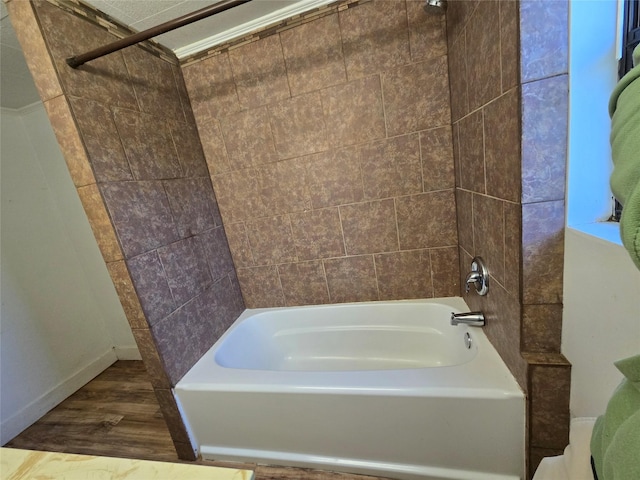 bathroom featuring wood finished floors, baseboards, and shower / washtub combination