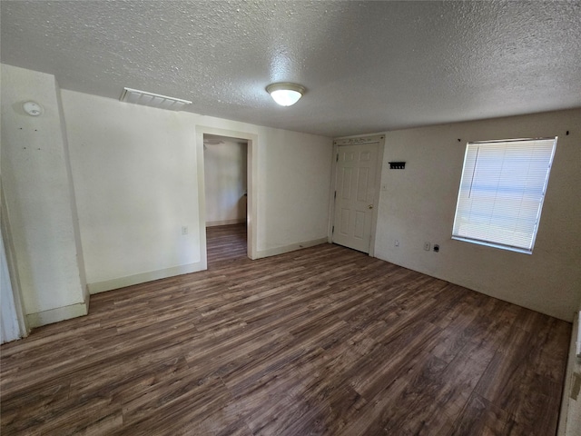 spare room with a textured ceiling, visible vents, and wood finished floors