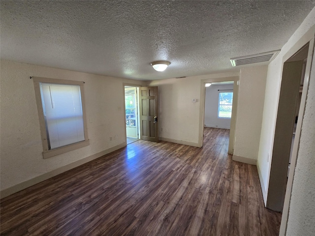 spare room with baseboards, visible vents, a textured ceiling, and wood finished floors