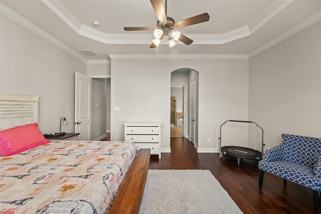 bedroom with a tray ceiling, arched walkways, visible vents, and wood finished floors
