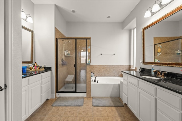 full bath featuring a garden tub, a sink, two vanities, tile patterned floors, and a shower stall