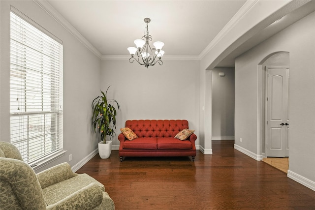 sitting room featuring wood finished floors, ornamental molding, an inviting chandelier, arched walkways, and baseboards