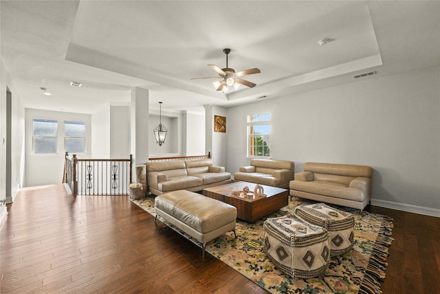 living area with visible vents, baseboards, a raised ceiling, and ceiling fan