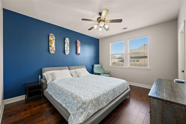 bedroom with baseboards, dark wood finished floors, visible vents, and a ceiling fan