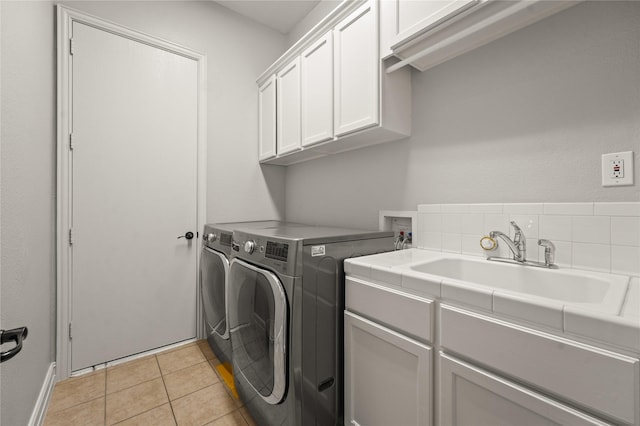 washroom with washing machine and dryer, a sink, cabinet space, and light tile patterned floors