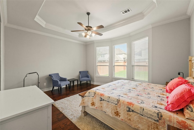 bedroom with a tray ceiling, crown molding, dark wood-type flooring, and visible vents