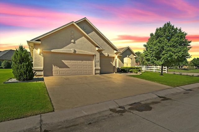 view of front of property with fence, a garage, stucco siding, concrete driveway, and a front lawn