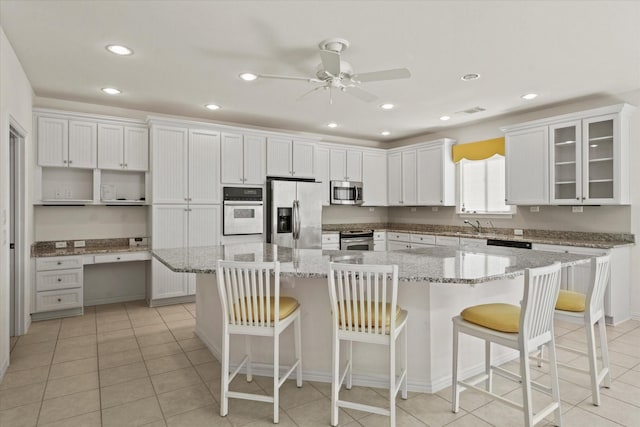 kitchen with recessed lighting, ceiling fan, a center island, white cabinets, and appliances with stainless steel finishes