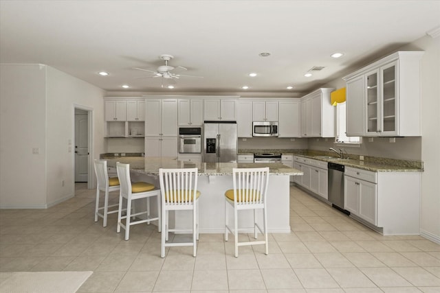 kitchen with a sink, stainless steel appliances, baseboards, a ceiling fan, and a kitchen island