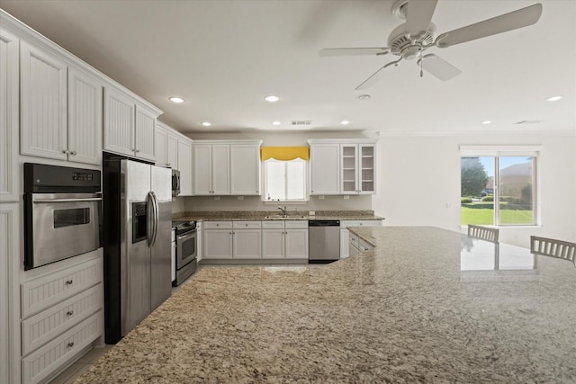 kitchen featuring white cabinets, stainless steel appliances, light stone countertops, and recessed lighting