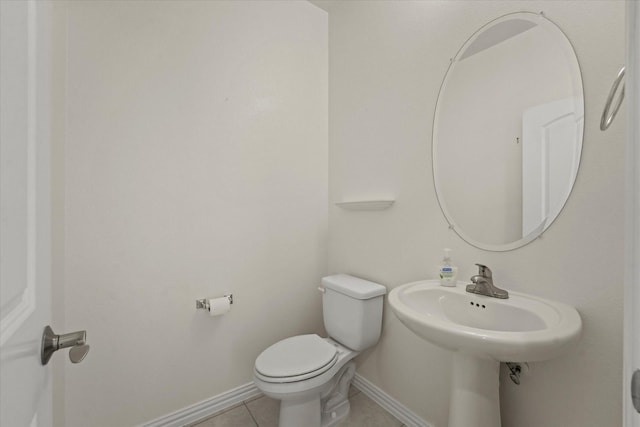 half bath with baseboards, tile patterned flooring, and toilet