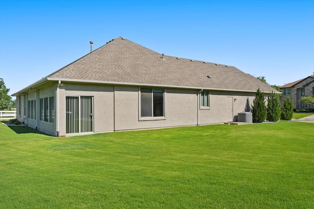 back of house with a shingled roof, a yard, stucco siding, and cooling unit