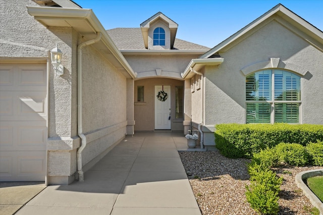 view of exterior entry featuring stucco siding and an attached garage