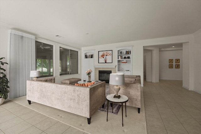 living area with light tile patterned floors, a fireplace, visible vents, baseboards, and built in shelves