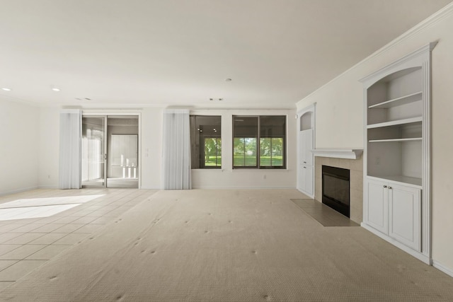 unfurnished living room with recessed lighting, built in shelves, crown molding, baseboards, and a tiled fireplace