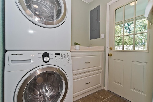 washroom with electric panel, laundry area, stacked washing maching and dryer, and dark tile patterned floors