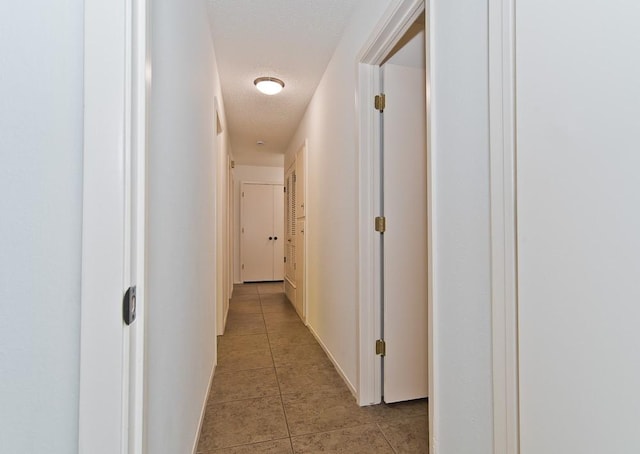 hallway featuring a textured ceiling and light tile patterned floors