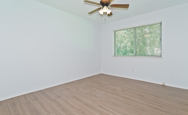 empty room featuring light wood finished floors, baseboards, and a ceiling fan