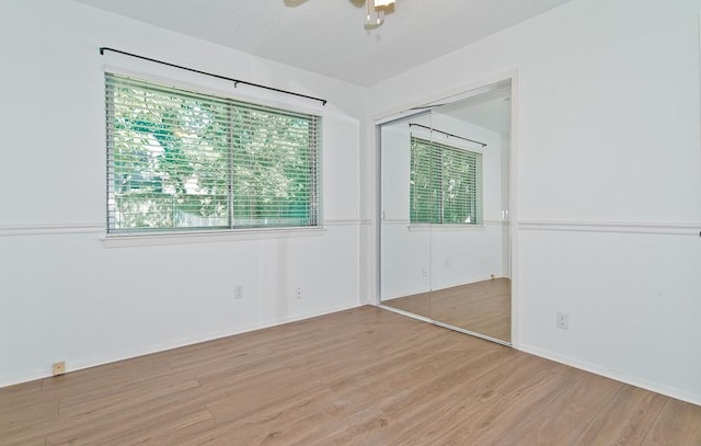 unfurnished bedroom featuring a closet, light wood-type flooring, baseboards, and ceiling fan