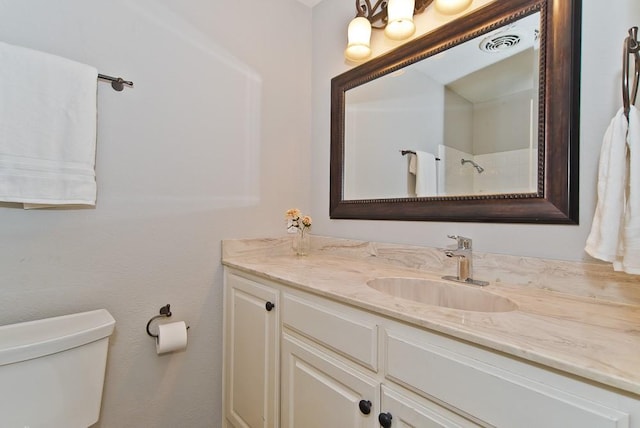 bathroom with walk in shower, toilet, visible vents, and vanity