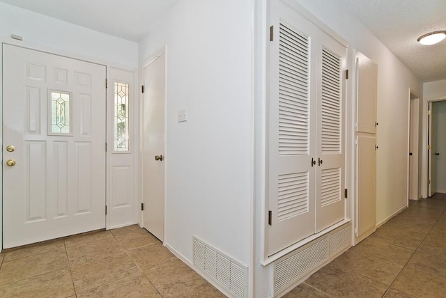 foyer featuring light tile patterned floors, baseboards, and visible vents
