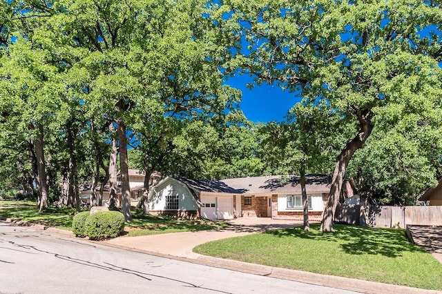 ranch-style house with fence, an attached garage, brick siding, driveway, and a front lawn