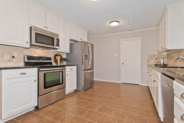 kitchen featuring a sink, dark countertops, stainless steel appliances, white cabinetry, and decorative backsplash