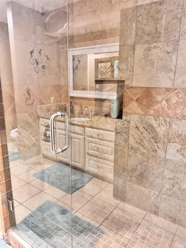 bathroom with a shower stall, tile walls, tile patterned flooring, and vanity