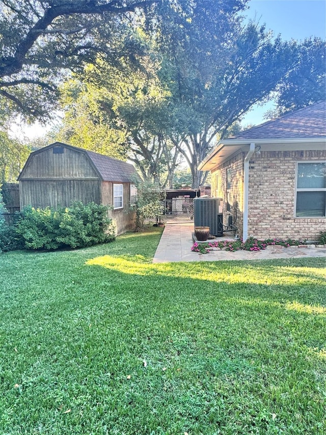 view of yard featuring a storage shed, a patio, fence, central air condition unit, and an outbuilding