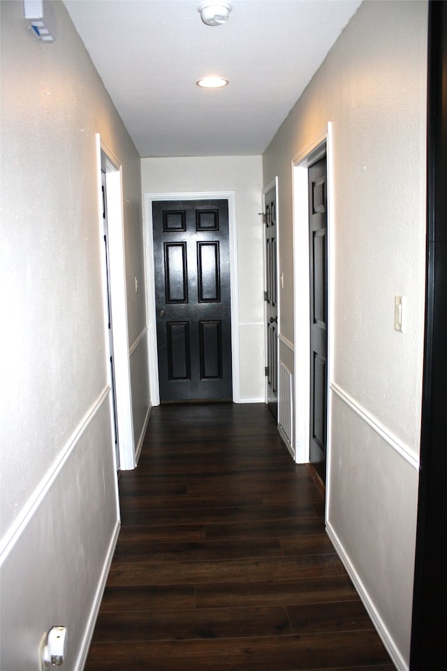 corridor featuring baseboards and dark wood finished floors