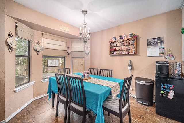 3811 Pelham Mnr, Arlington, TX 76016 - dining space with a notable chandelier, stone tile flooring, baseboards, and a textured wall