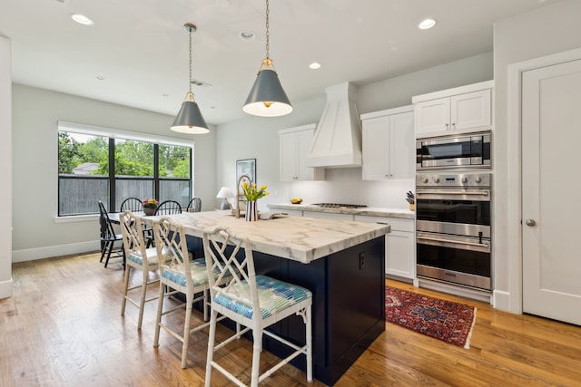 431 Blanning Dr, Dallas, TX 75218 - kitchen with pendant lighting, custom exhaust hood, a kitchen bar, white cabinets, and appliances with stainless steel finishes