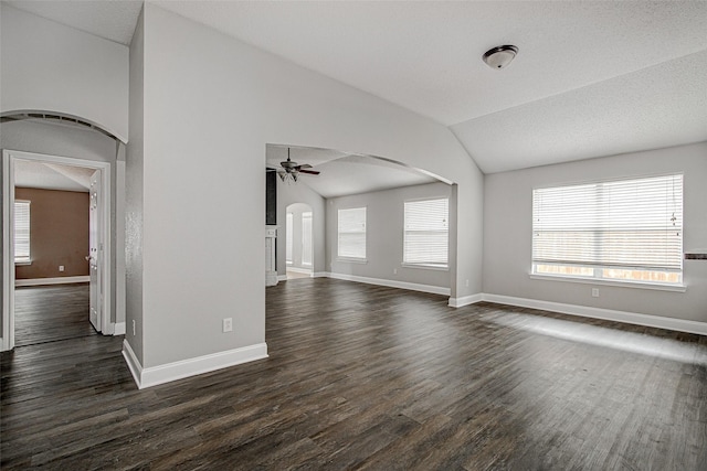 1001 Benjamin Dr, Burleson, TX 76028 - unfurnished living room with vaulted ceiling, ceiling fan, dark wood-style flooring, a wealth of natural light, and arched walkways