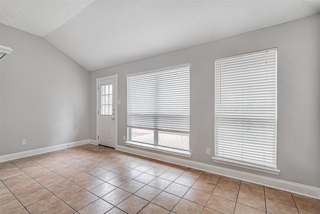 1001 Benjamin Dr, Burleson, TX 76028 - empty room with light tile patterned floors, baseboards, a textured ceiling, and vaulted ceiling
