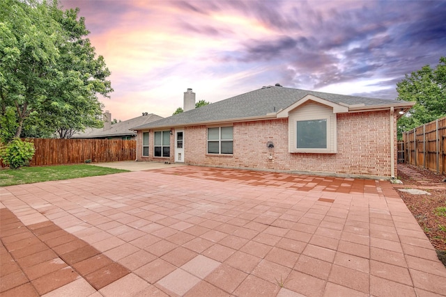 1001 Benjamin Dr, Burleson, TX 76028 - back of property at dusk featuring a fenced backyard, a patio area, a chimney, and brick siding