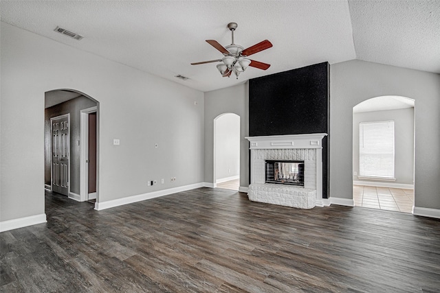 1001 Benjamin Dr, Burleson, TX 76028 - unfurnished living room featuring a brick fireplace, visible vents, ceiling fan, arched walkways, and vaulted ceiling