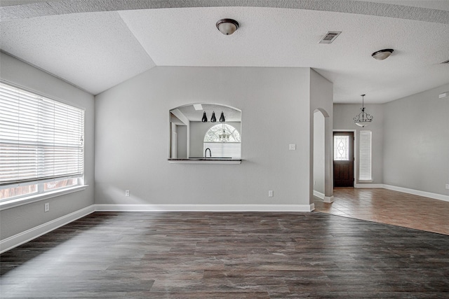 1001 Benjamin Dr, Burleson, TX 76028 - unfurnished living room featuring dark wood finished floors, visible vents, arched walkways, a chandelier, and lofted ceiling