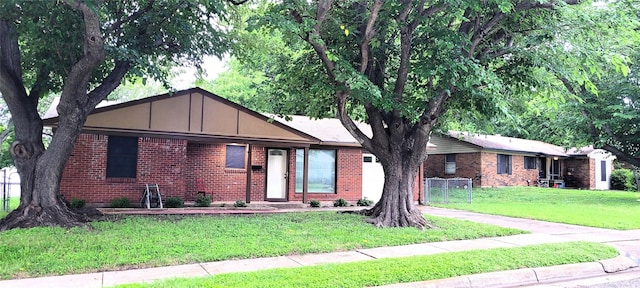 single story home featuring a front lawn, brick siding, and board and batten siding