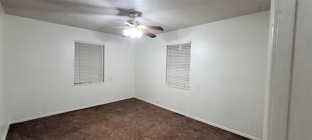 unfurnished room with dark colored carpet, a textured ceiling, baseboards, and a ceiling fan