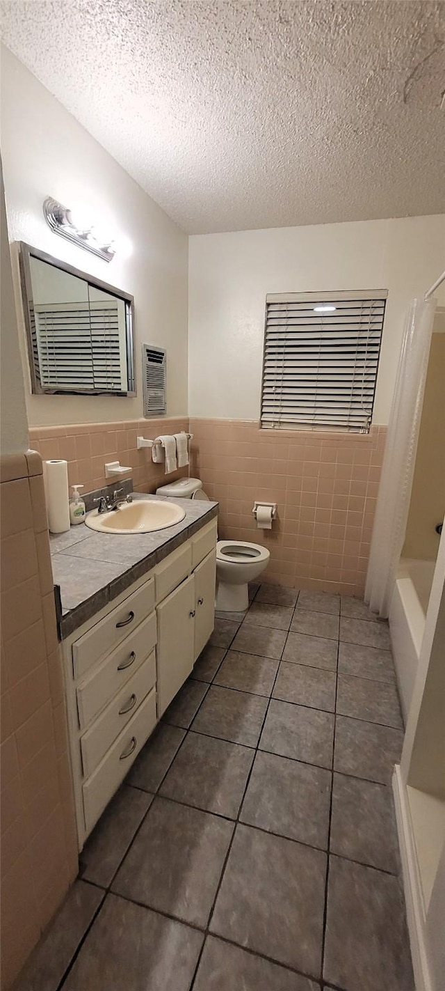 full bath with tile walls, toilet, a wainscoted wall, vanity, and tile patterned flooring
